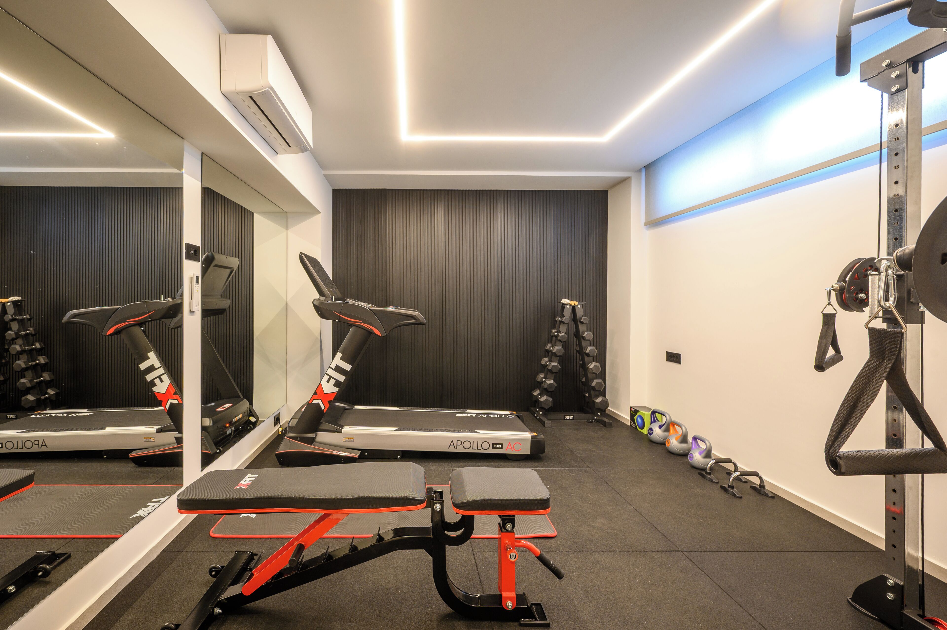 Un gimnasio con cintas de correr, una banca y pesas.