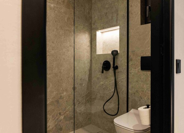 A modern bathroom with a glass-enclosed shower, a toilet, and a towel rack. - Anesea City (Heraklion)