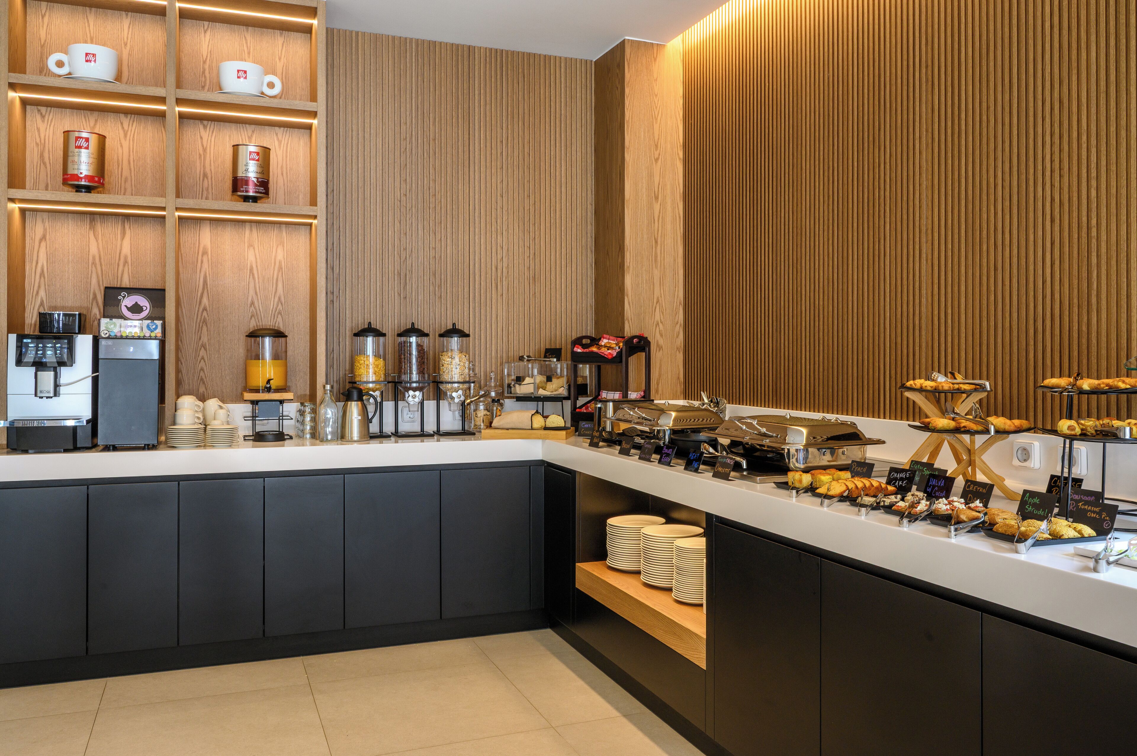 Un bar à petit-déjeuner moderne, équipé de machines à café, d’un distributeur de jus et proposant une variété de viennoiseries.