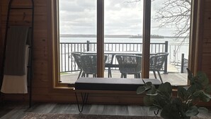A room with a large window, a wooden table, a bench, and a plant. - Lakefront Escape with Loft & Summer Bunkhouse — Steps from the Water & Trails! (Waubun)