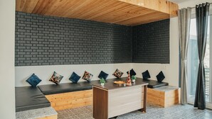 Ein modernes Zimmer mit Holzboden, schwarzer Ziegelwand und einer Sitzecke mit Kissen und einem kleinen Tisch.