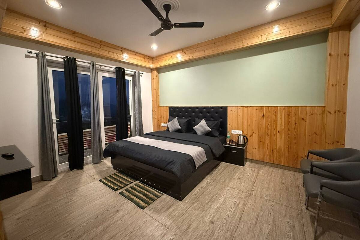A modern bedroom with a large bed, a ceiling fan, a nightstand, and a view through a sliding door.