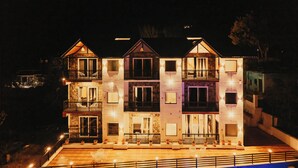 Ein mehrstöckiges Gebäude mit Balkonen, großen Fenstern und einer gut beleuchteten Fassade bei Nacht.