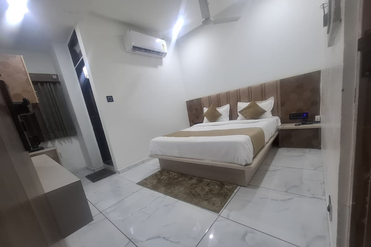 A modern bedroom with a bed, bedside tables, an air conditioning unit, and a ceiling fan.