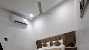 Un dormitorio moderno con cama, ventilador de techo, aire acondicionado y mesita de noche.