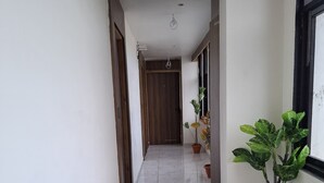 Un pasillo con piso de mármol, puertas de madera y plantas en macetas.