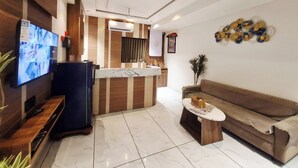 Una sala moderna con televisor, sofá, mesa de centro y una cocina con barra.