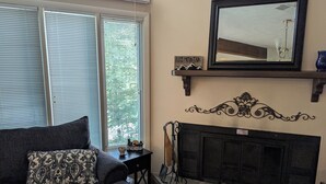 Ein Wohnzimmer mit Kamin, einer Couch mit gemusterten Kissen, einem Spiegel über dem Kamin und einem dekorativen Wandbild.