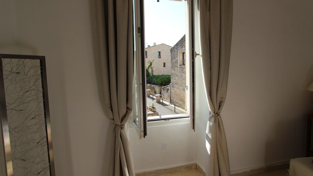 Una habitación con ventana, cortinas y vistas a edificios.