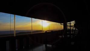 Una stanza con una grande finestra che si affaccia su un tramonto.
