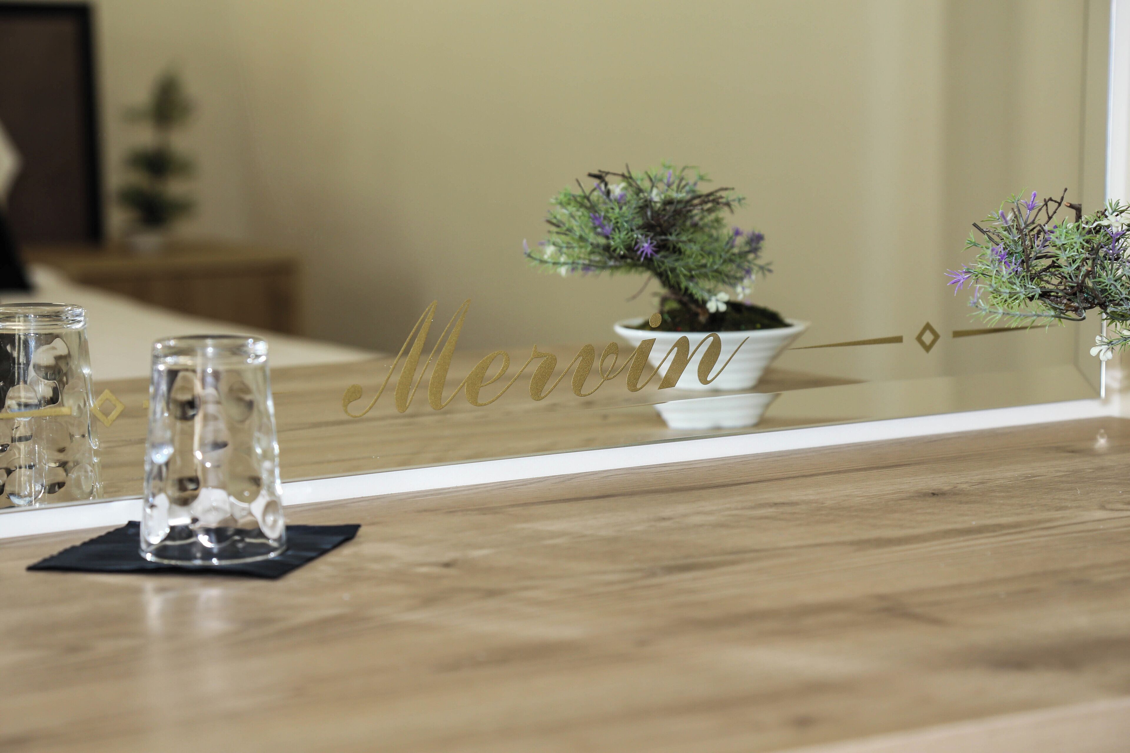 Une table en bois, sur laquelle se trouvent un vase en verre et une petite plante en pot.