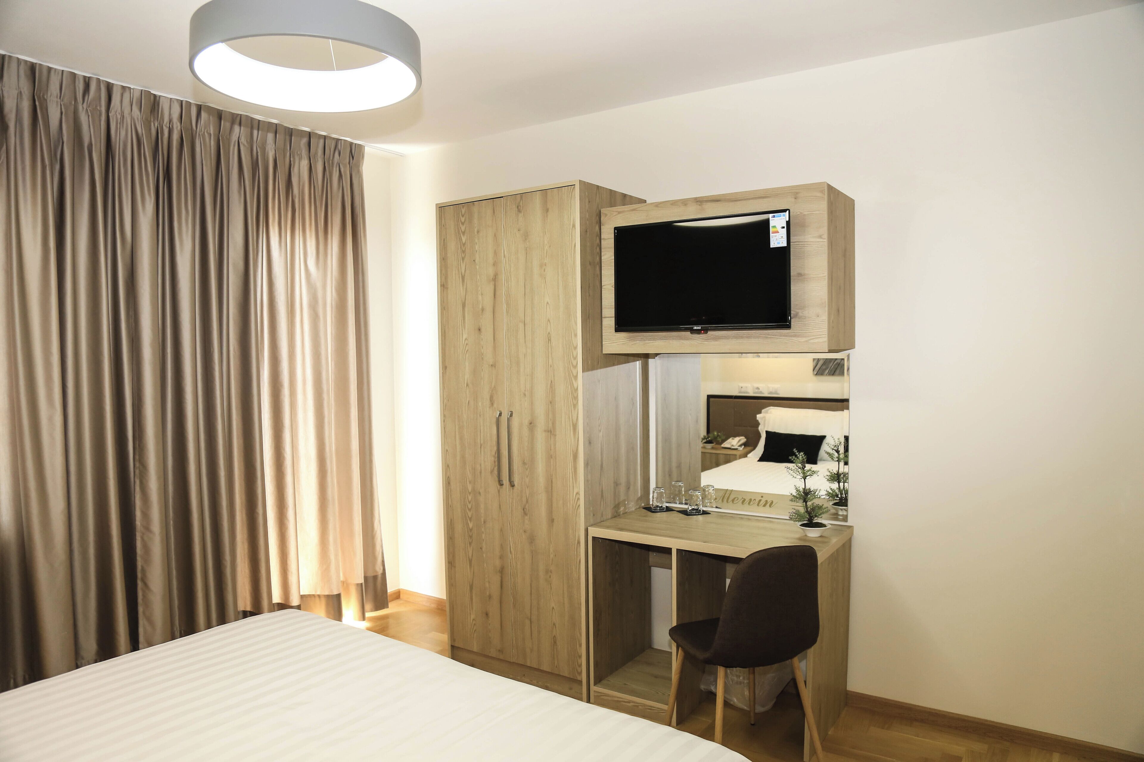 Une chambre d’hôtel comprenant un lit, un bureau avec une chaise, un téléviseur fixé au mur et une armoire.