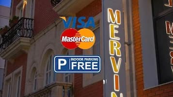 Placa de hotel com a inscrição 'HOTEL MERVIN' e 'ESTACIONAMENTO COBERTO GRÁTIS'.