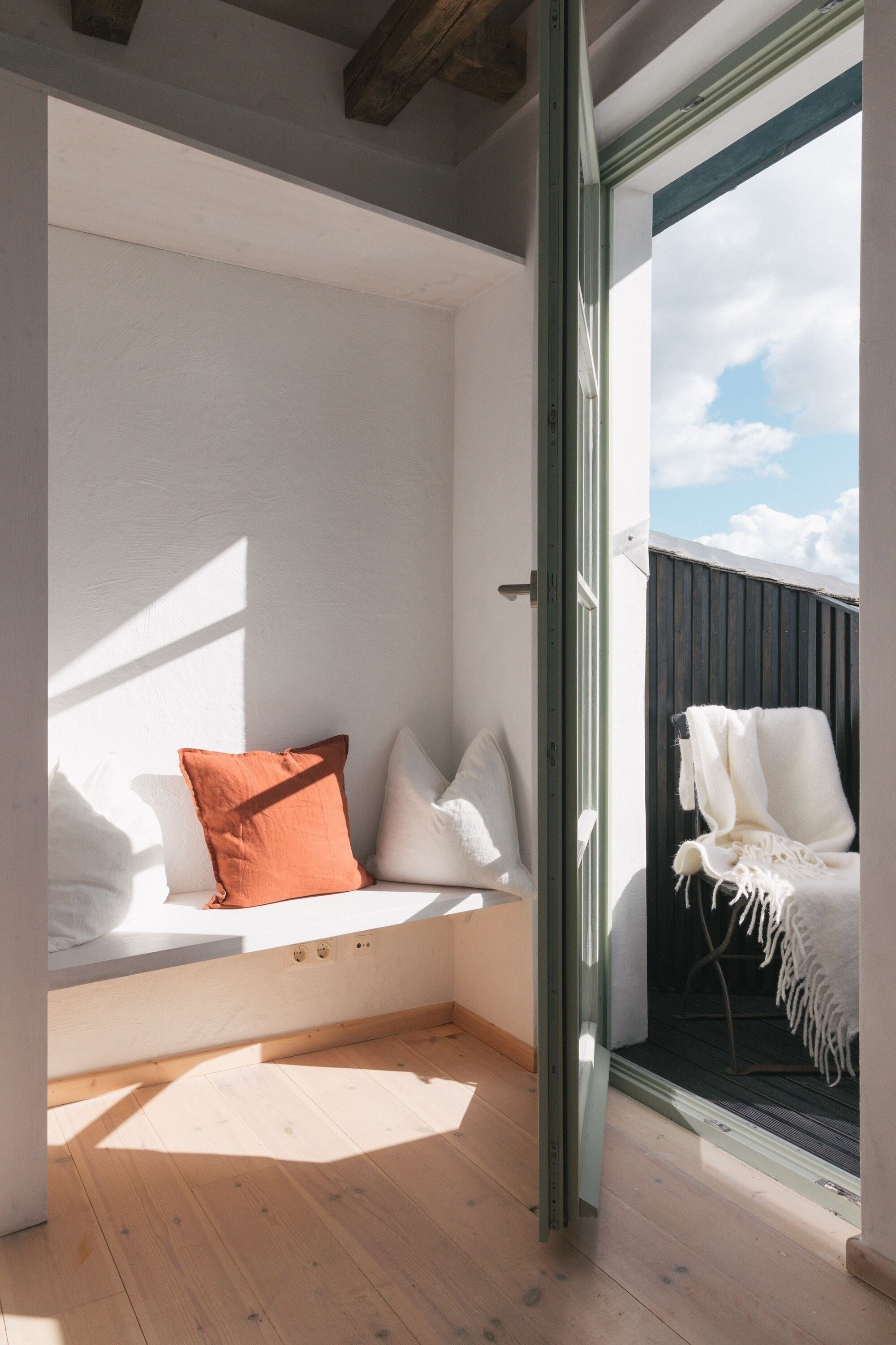 Una habitación con un banco integrado, una ventana y vista al cielo.