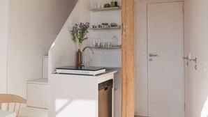 Kompakti keittiö, jossa on puinen ruokapöytä, sisäänrakennettu pesuallas ja portaat, jotka johtavat ylemmälle tasolle.