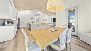 Een moderne keuken met witte kastjes, een houten eettafel en een hangende lamp.