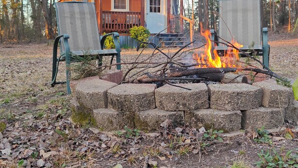 A rustic cabin with a fire pit in front, surrounded by trees. - Peacefull Cabin in the Woods with heat/air conditioning (Marietta)