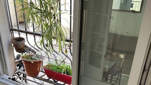 A room with a window overlooking a balcony, a radiator, and a wooden staircase. - Charming apartment Paris center république (Paris)