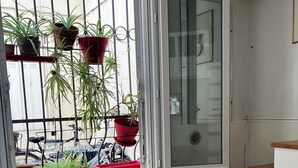 A room with a large window, a radiator, a wooden chair, a small table, and a white cabinet. - Charming apartment Paris center république (Paris)