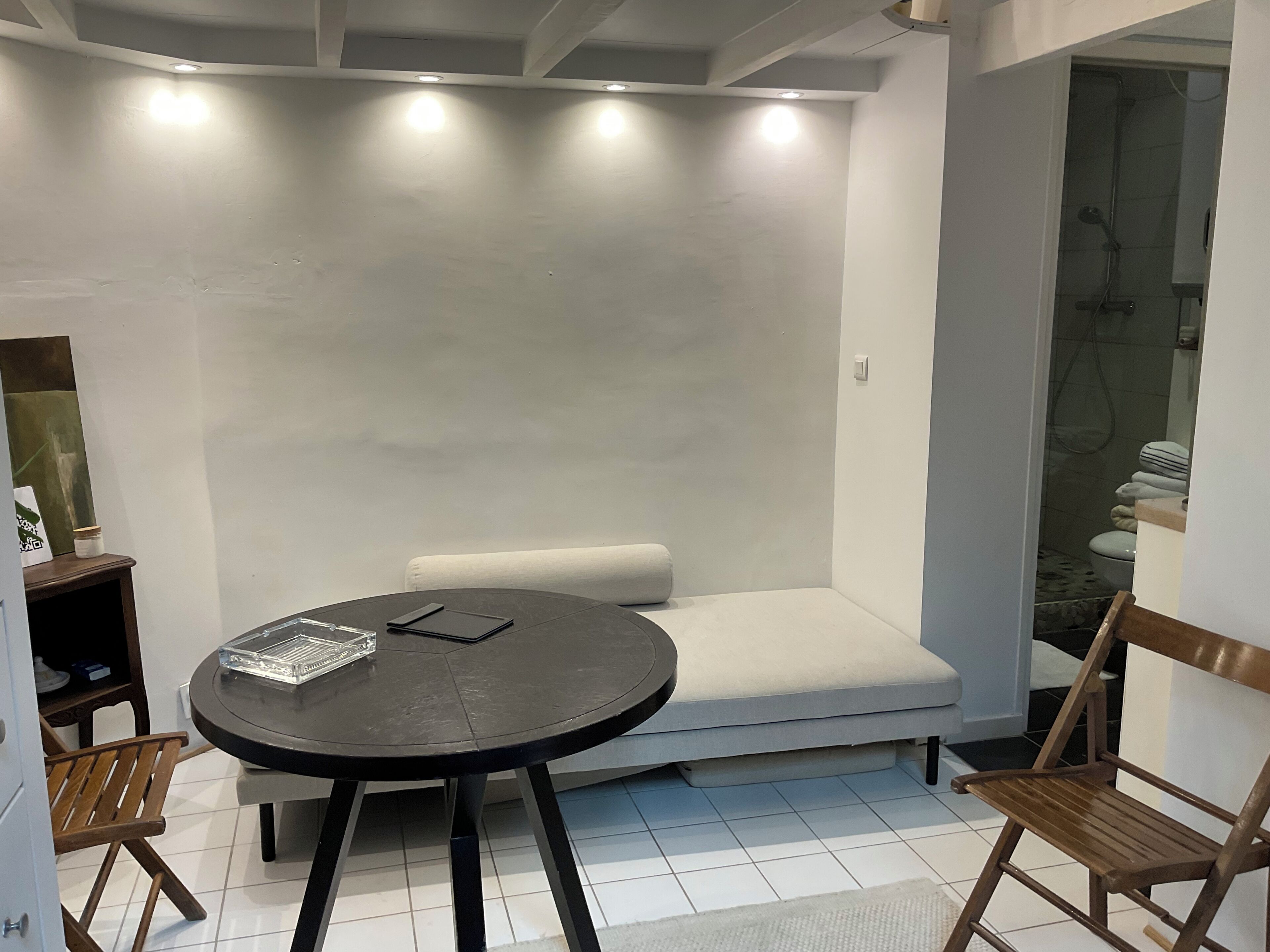 Een moderne kamer met een ronde tafel, een bank en een douchehoek.