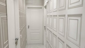 A hallway with white doors and a marble floor.
