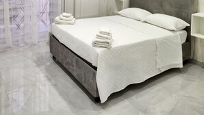 A modern bedroom with a bed, a nightstand, a wardrobe, and a shower area.