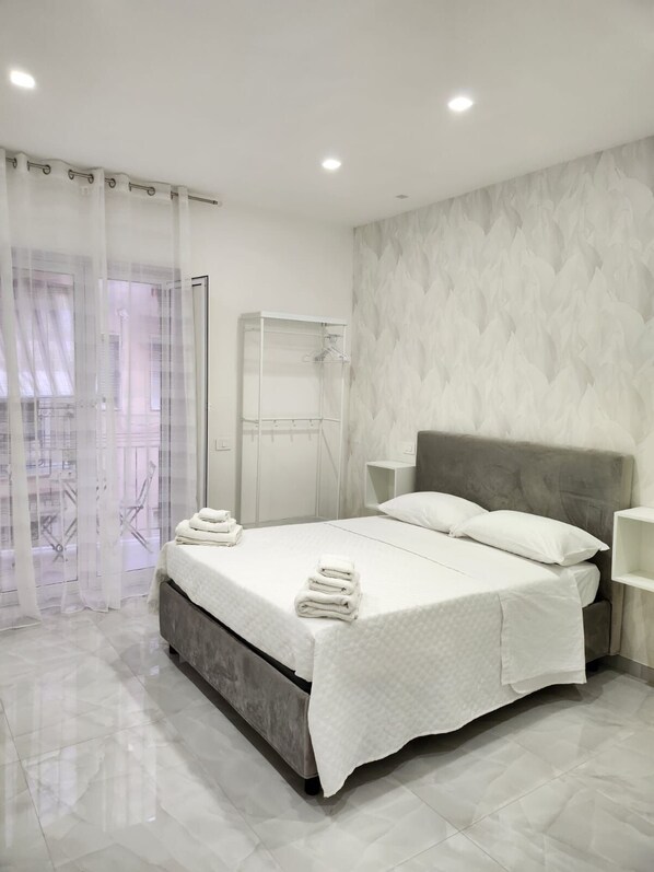 A modern bedroom with a bed, a nightstand, a wardrobe, and a shower area. - Daisy House n1 (Napoli)
