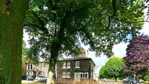 A house with a large tree in front, a grassy area, and a road with parked cars. - Little House, 17 Church Square (Harrogate)