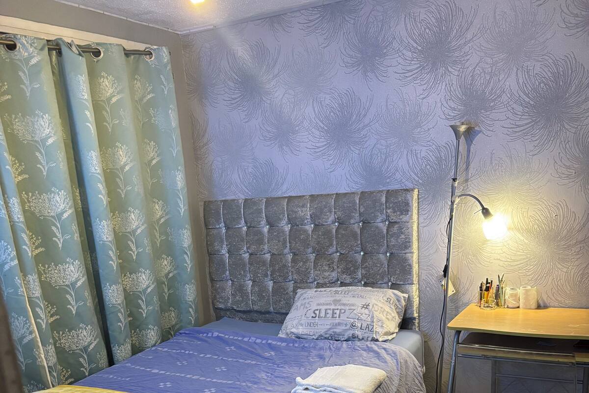 A neatly arranged bedroom with a bed, a desk, and a chair.