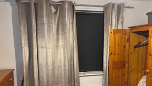 A room with a window, a radiator, a wooden wardrobe, and a wooden dresser. - Cosy room for Female Couple and Families (Manchester)