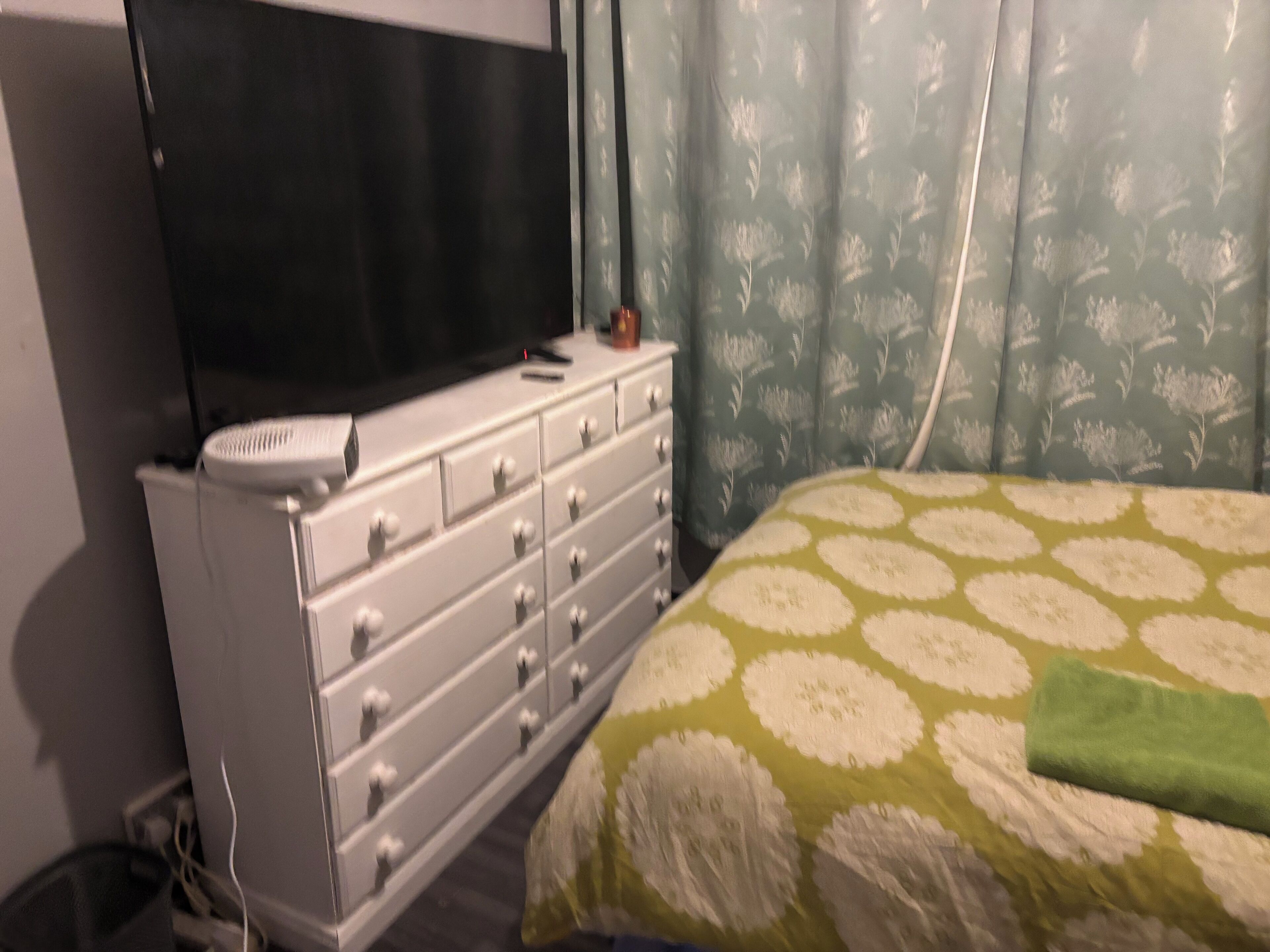 A room with a bed, a dresser, and a television.