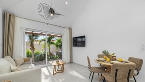 Ein modernes Wohnzimmer mit einer Couch, einem Esstisch, Stühlen und einem an der Wand befestigten Fernseher.