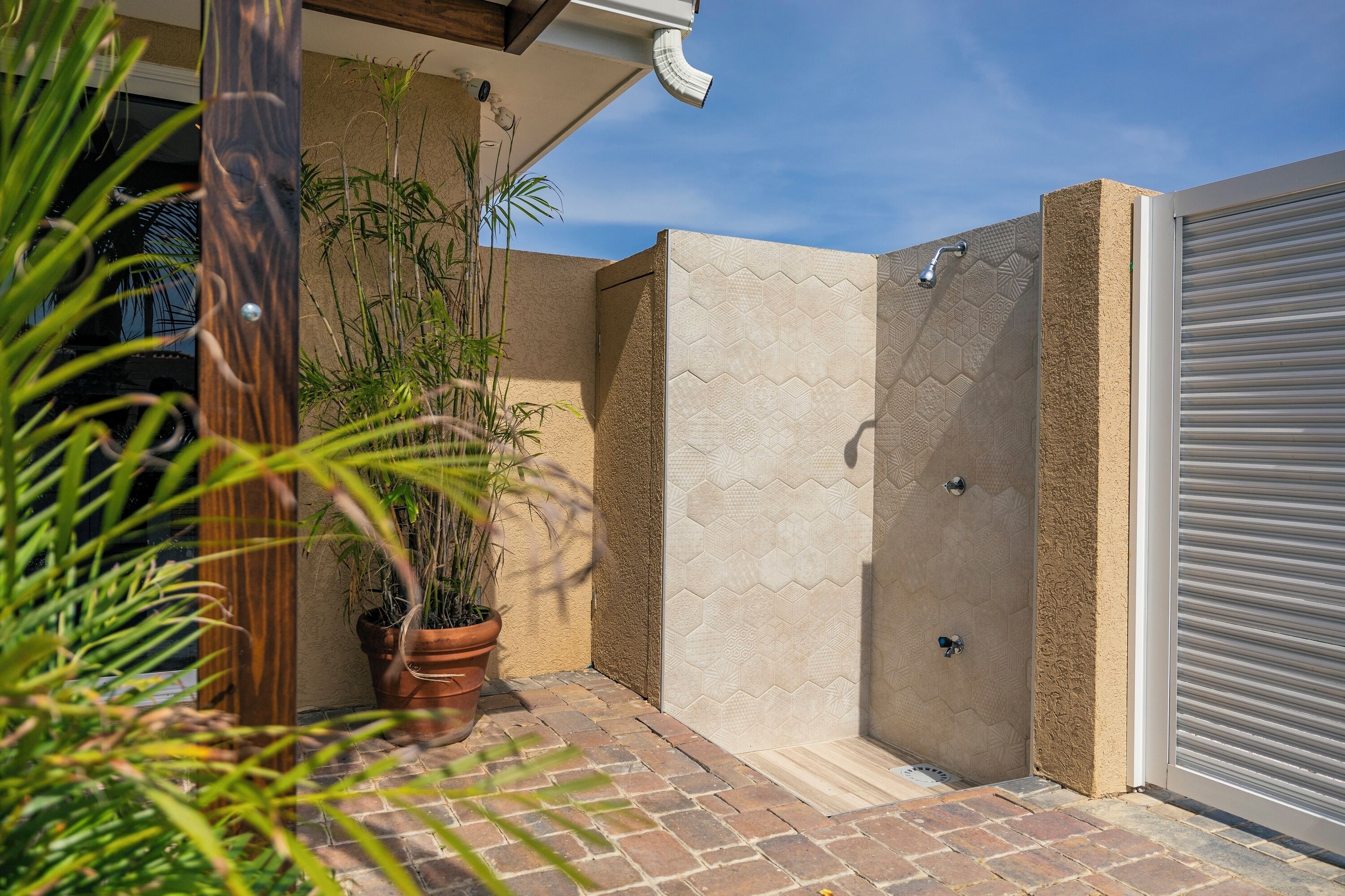 A patio area with a brick floor, a potted plant, and a sliding door.