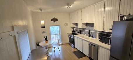 A modern kitchen with white cabinetry, a built-in oven, a dishwasher, and a large refrigerator.