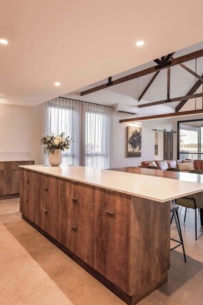 A spacious kitchen with a large island, wooden cabinets, and a dining area with a sofa.
