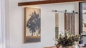 Een woonkamer met een groot schilderij, een schuifdeur en een vaas met planten.