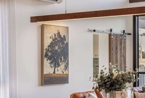 En stue med et stort maleri, en skydedør og en vase med planter.