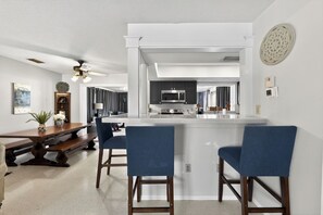 Une cuisine moderne dotée d’un îlot central, de meubles de couleur sombre et d’un ventilateur de plafond.
