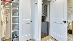 A compact, well-organized closet with clear storage bins, a hanging robe, and a microwave. - Single Tree Haven + Optional Rental Car Delivery (Superior)