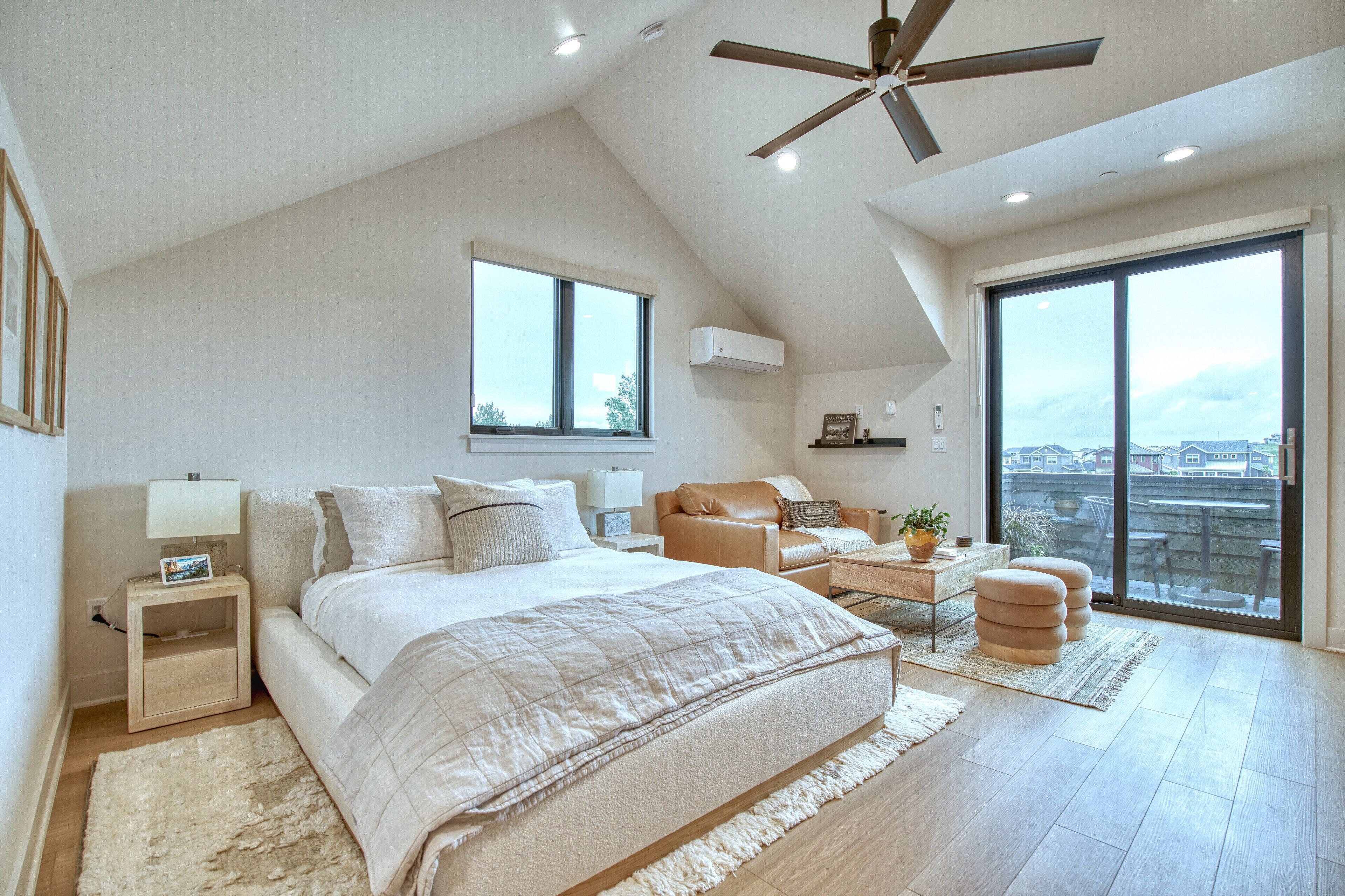 Ein modernes Schlafzimmer mit einem großen Bett, einem Schreibtisch, einem Stuhl und einem Balkon mit Blick auf die Stadt.