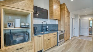 A modern kitchen with wooden cabinets, a microwave, a sink, and an oven. - Single Tree Haven + Optional Rental Car Delivery (Superior)
