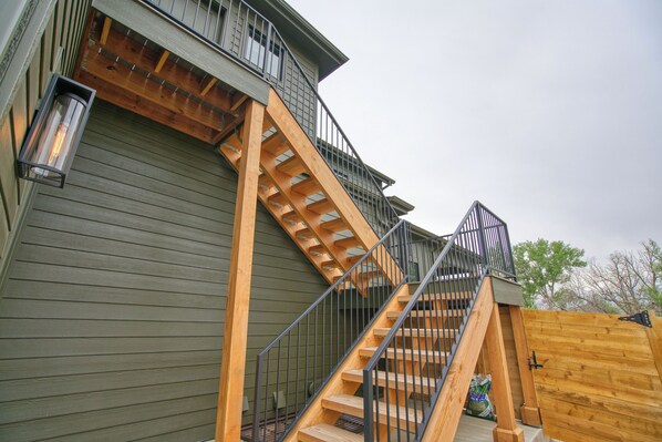 A wooden staircase leading to a balcony with a metal railing.