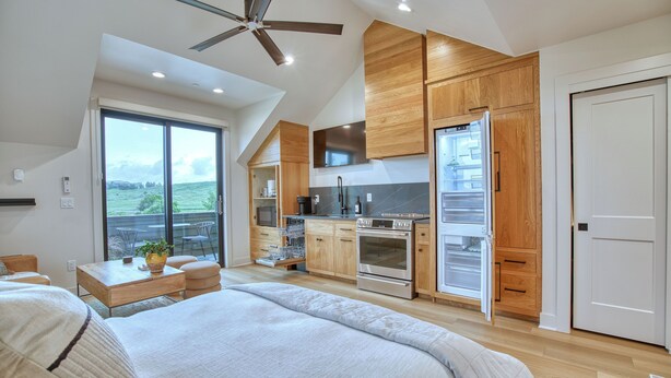A modern bedroom with a large bed, a ceiling fan, and a view of the outdoors. - Single Tree Haven + Optional Rental Car Delivery (Superior)