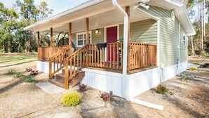 A single-story house with a covered porch, a red door, and a small front yard with landscaping. - Lovely cozy cottage with AC in charming Waycross (Waycross)