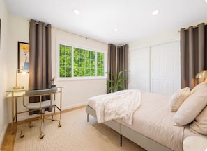 Une chambre à coucher avec un lit, un bureau, une fenêtre avec des rideaux et une porte.