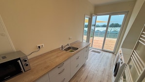 Een moderne keuken met een houten aanrecht, een ingebouwde magnetron en een spoelbak.