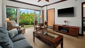 A living room with a sofa, coffee table, chairs, a television, and a ceiling fan. - Fall Getaway at Oceanfront Waipouli Beach Resort (Kapaʻa)