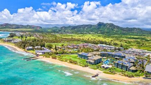 A coastal resort with beachfront properties, a swimming pool complex, and a view of the ocean and mountains. - Fall Getaway at Oceanfront Waipouli Beach Resort (Kapaʻa)