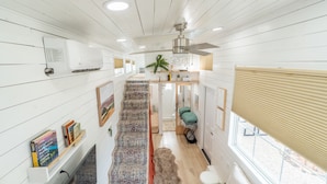 A spacious hallway with a patterned carpet, a ceiling fan, and a window with blinds.