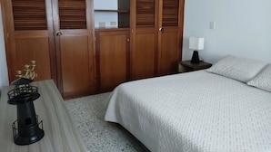 A bedroom with a bed, a nightstand, a lamp, a wardrobe, and a small table with a decorative item. - Central and spacious apartment in Rionegro (Rionegro)